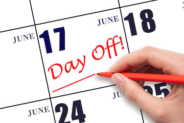 Hand writing text DAY OFF and drawing a line on calendar date 17 June. Vacation planning concept.