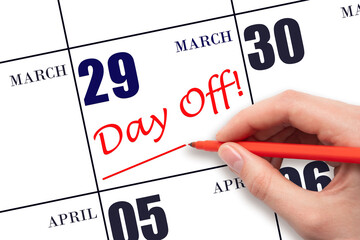 Hand writing text DAY OFF and drawing a line on calendar date 29 March. Vacation planning concept.