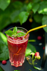 Raspberry, basil detox water, lemonade, Summer cold drink on a black background, outdoor garden fresh bush, sunlight, Vegan, diet, organic natural