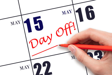 Hand writing text DAY OFF and drawing a line on calendar date 15 May. Vacation planning concept.