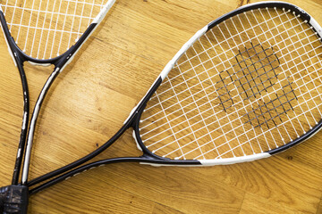 Two old squash rackets lie on a parquet background