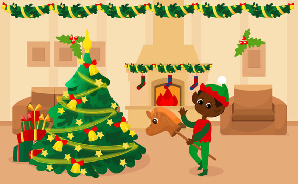 In the room near the Christmas tree there is a happy elf boy on a toy horse. Home for Christmas or Christmas Eve inside. The room has a fireplace with fire, an armchair and a sofa. 
