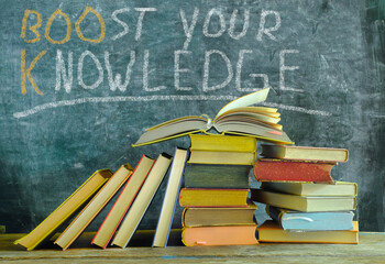 open book in front of a black board with slogan boost your knowledge,learning,education and back to...