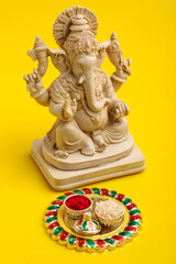 Lord Ganesha Sculpture on yellow background.