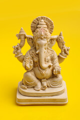 Lord Ganesha Sculpture on yellow background.