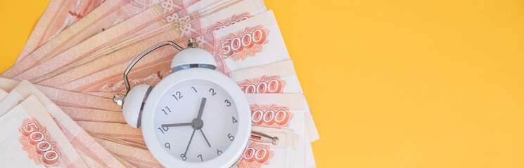 Time value of money concept.analog clock on russian ruble banknote, depicting receiving money today...