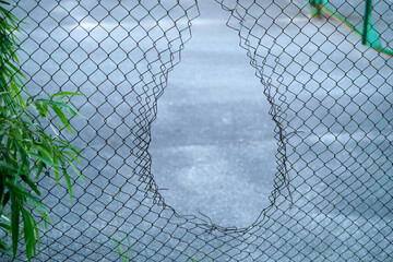 Hole in the fence. Mesh wire boundary. Steel mesh barrier fence. Chain link fence with Hole.