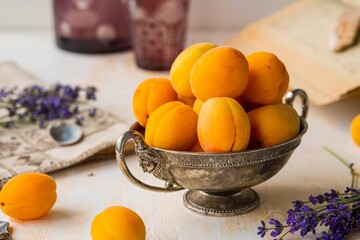 Ripe juicy apricots in a metal vintage vase on a light concrete background. Vintage style.