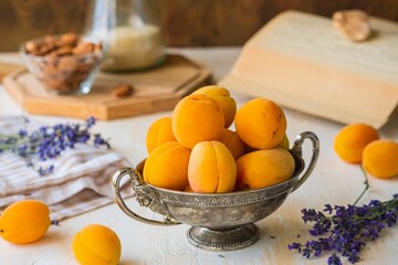 Ripe juicy apricots in a metal vintage vase on a light concrete background. Vintage style.
