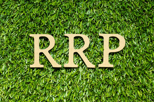 Wood alphabet letter in word RRP (Abbreviation of recommended retail price) on green grass background