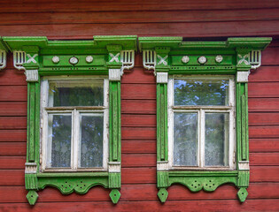 The beautiful old windows with beautifully designed platbands window on an old wooden house in...