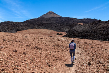 Woman with backpack on volcanic desert terrain hiking trail leading to summit volcano Pico del Teide, Mount Teide National Park, Tenerife, Canary Islands, Spain, Europe. Solidified lava, ash, pumice © Chris