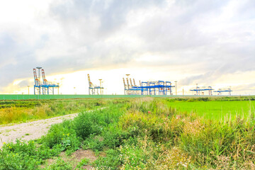 Fototapeta na wymiar Industrial area cranes red tower lighthouse dyke seascape panorama Germany.
