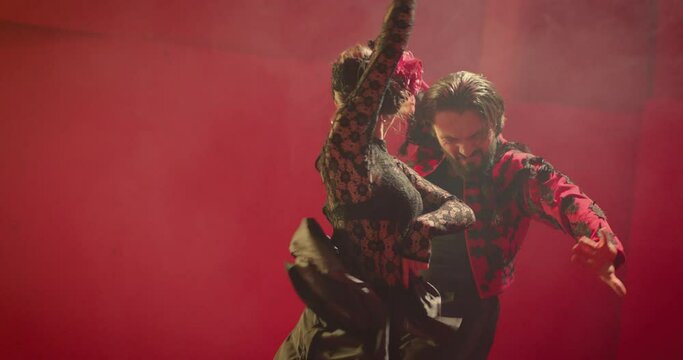 Beautiful couple dancing latin dance . Professional dancers dancing flamenco, rumba or salsa on red background. Couple in spanish dress performs dance movement. Shot ARRI ALEXA Cinema Camera .