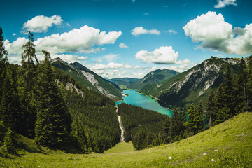 Achensee, lake in sunset light in Tirol Alps. Beautiful landscape with green trees, meadow, rocks and blue sky with clouds in the mountains. Summer landscape scene from nature, Tirol Alps, Austria