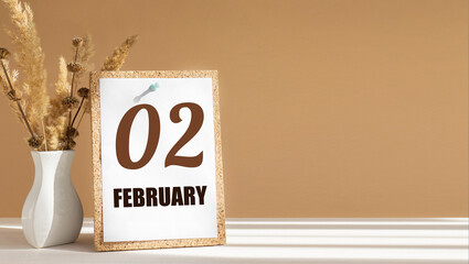 february 2. 2th day of month, calendar date.White vase with dead wood next to cork board with numbers. White-beige background with striped shadow. Concept of day of year, time planner, winter month