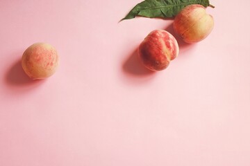 Juicy peaches with leaves on a pink background. Fresh fruits on the table. still life photography
