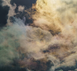 Diffraction of light on drops of supercooled water in clouds, rainbow clouds against the blue sky in clear sunny weather, irisation of cumulus clouds, optical phenomenon, spectral colors