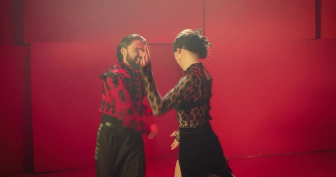 Beautiful couple dancing latin dance . Professional dancers dancing flamenco, rumba or salsa on red background. Couple in spanish dress performs dance movement. Shot ARRI ALEXA Cinema Camera .