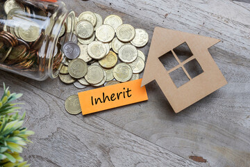 INHERIT was written on the post-it note with a house model and pile of coins flowing from the glass jar