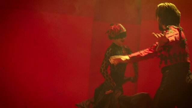 Beautiful couple dancing latin dance . Professional dancers dancing flamenco, rumba or salsa on red background. Couple in spanish dress performs dance movement. Shot ARRI ALEXA Cinema Camera .