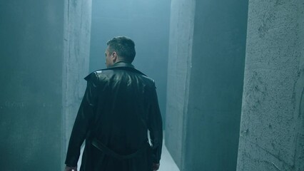 Rear back view of unknown man walking , standing or running inside dark maze. Dark corridor with concrete walls . Footage of mystical video. Shot on ARRI ALEXA Cinema Camera in slow motion