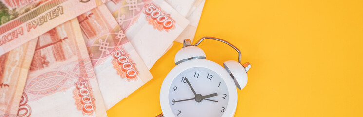 analog clock near russian banknote, money.It is time to pay. Credit debt. Piggy bank pink pig and little alarm clock. Financial crisis. Economics and finance. Banking account.