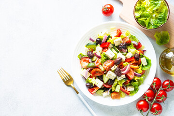 Greek salad. Vegetable salad with tomato, cucumber, feta cheese and olive oil. Top view on white stone table.