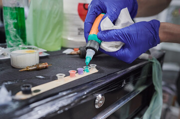 Tattoo studio scene. Color ink refilling. Color palette on the work table of a tattoo artist to use in a design tattooed on the skin.