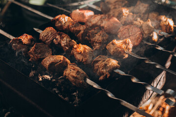Traditional Kebab. Juicy roasted hot meat on iron skewers. Barbecue.  Fresh, home-made on grill fire meat pork shashlik kebab on a sunny day close up outdoors  at back yard.  picnic.  Tasty BBQ food