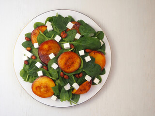 Plate with salad of spinach, cheese, peaches