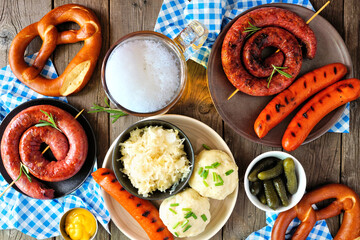 Traditional German Oktoberfest meal. Top down table scene over a dark wood background. Beer,...