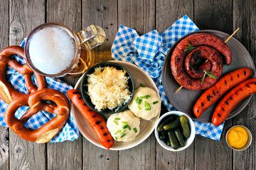 Classic German Oktoberfest meal. Above view table scene over a dark wood background. Beer, sausage,...
