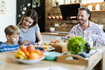  Young happy family enjoying in their breakfast time in dining room