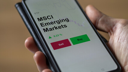 Un investisseur analyse un fonds etf msci emerging markets sur un graphique. Un téléphone affiche...