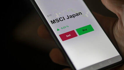Un investisseur analyse un fonds etf msci japan sur un graphique. Un téléphone affiche le cours...