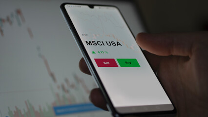 Un investisseur analyse un fonds etf msci usa sur un graphique. Un téléphone affiche le cours de l'ETF MSCI USA