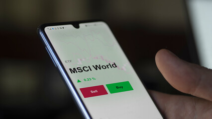 Un investisseur analyse un fonds etf msci world sur un graphique. Un téléphone affiche le cours...