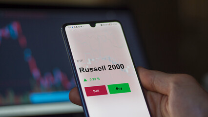 Un investisseur analyse un fonds etf russell 2000 sur un graphique. Un téléphone affiche le cours de l'ETF Russell 2000