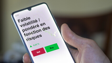 Un investisseur analyse un fonds etf faible volatilité / pondéré en fonction des risques sur un graphique. Un téléphone affiche le cours de l'ETF Faible volatilité / pondéré en fonction des risques