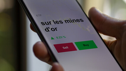 Un investisseur analyse un fonds etf sur les mines d'or sur un graphique. Un téléphone affiche le cours de l'ETF. Texte en français francais sur les mines d'or