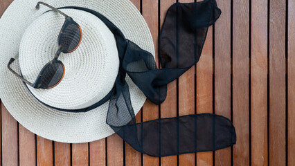 Straw women's hat with glasses on a wooden background