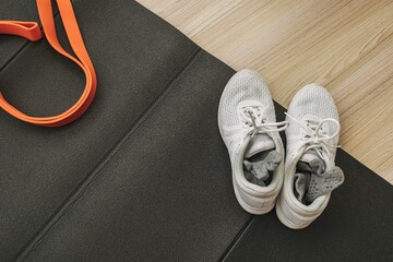 Set of exercise shoes rubber band and workout mat on the home floor.