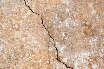 Big downward diagonal crack on old concrete brown wall. Horizontal photo. Close-up. Copy space. Selective focus.