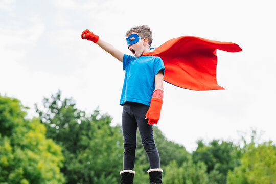 Excited boy in superhero costume in park