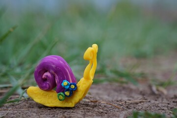 Snail figurine decorated with a flower on a background of green grass. Springtime.