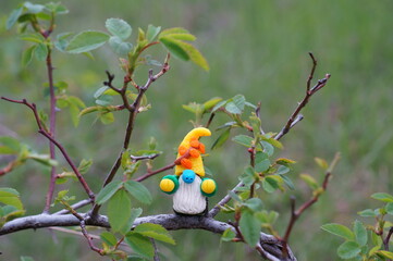 A figurine of a dwarf made of plasticine on a tree branch.