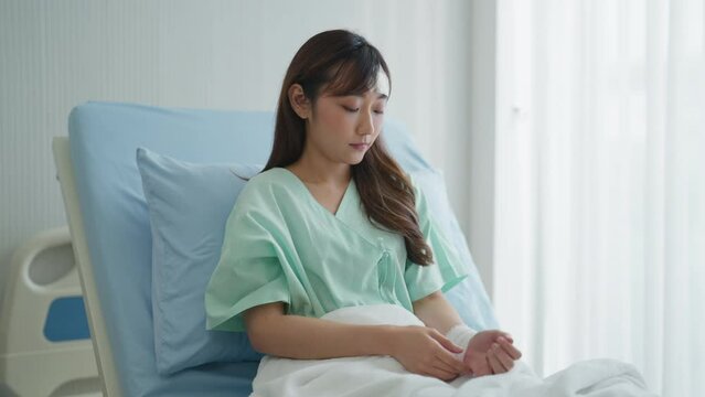 Sad female patient sitting in hospital bed. She was sad about her injuries. Insurance, Healthcare, Lifestyle, Sadness, Hospital, Hope concept.