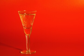 A glass of champagne on a red background. Close-up.