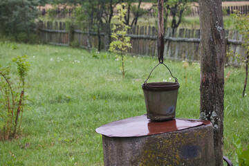 Old village well made of concrete circles.  A bucket is hung over it.